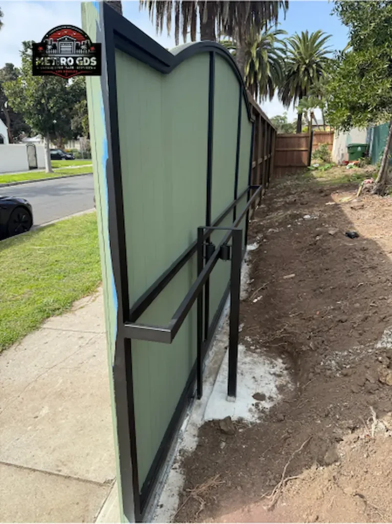 Green metal gate installation with black metal framing by Metro GDS Inc