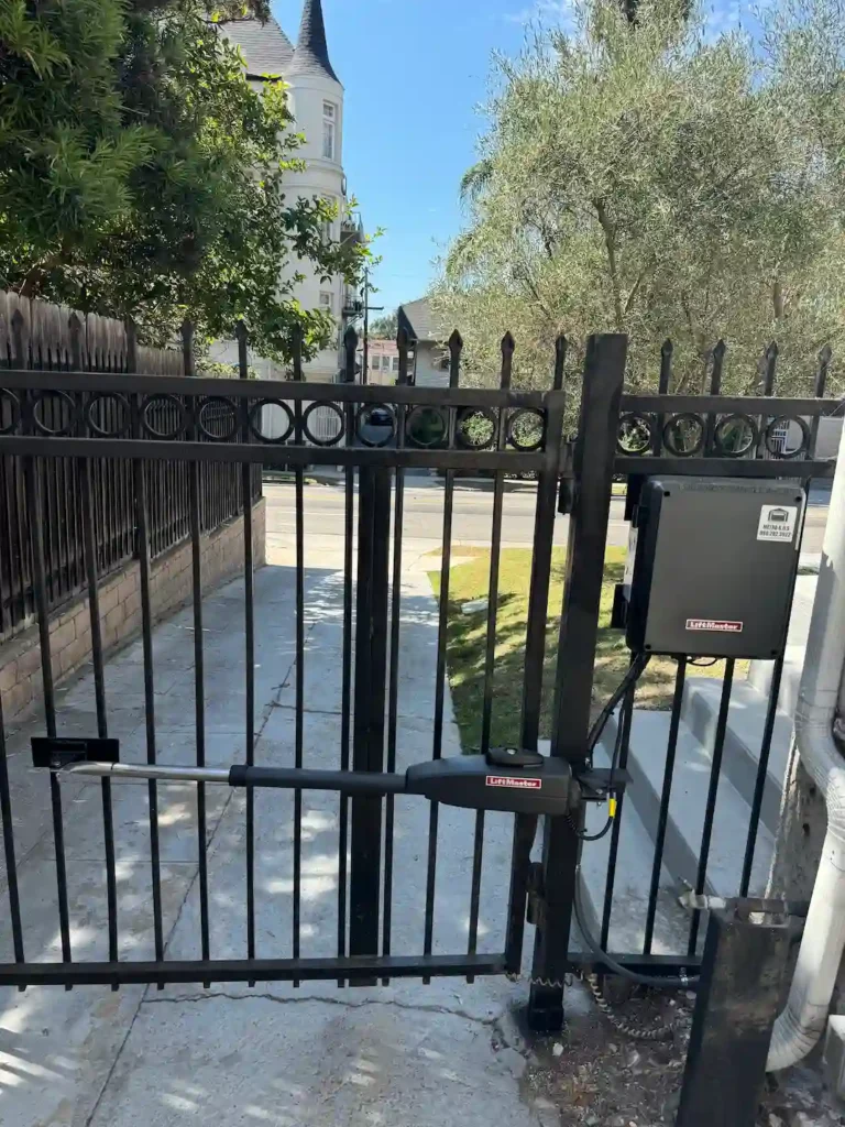 Automatic gate opener installed on a black wrought iron gate by Metro GDS Inc