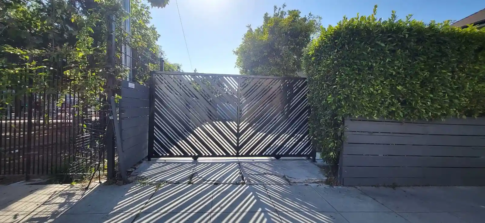 Modern metal driveway gate with diagonal slat design installed by Metro GDS Inc