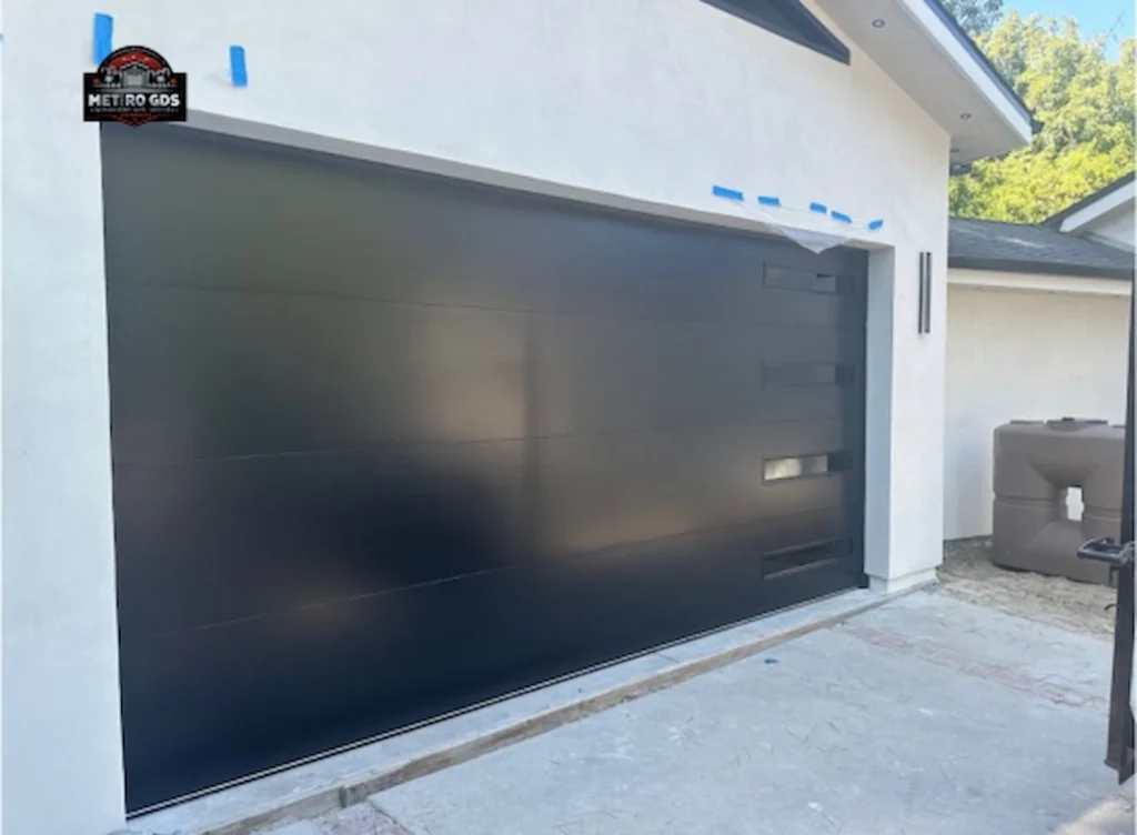 Sleek modern black garage door with horizontal panels installed by Metro GDS Inc