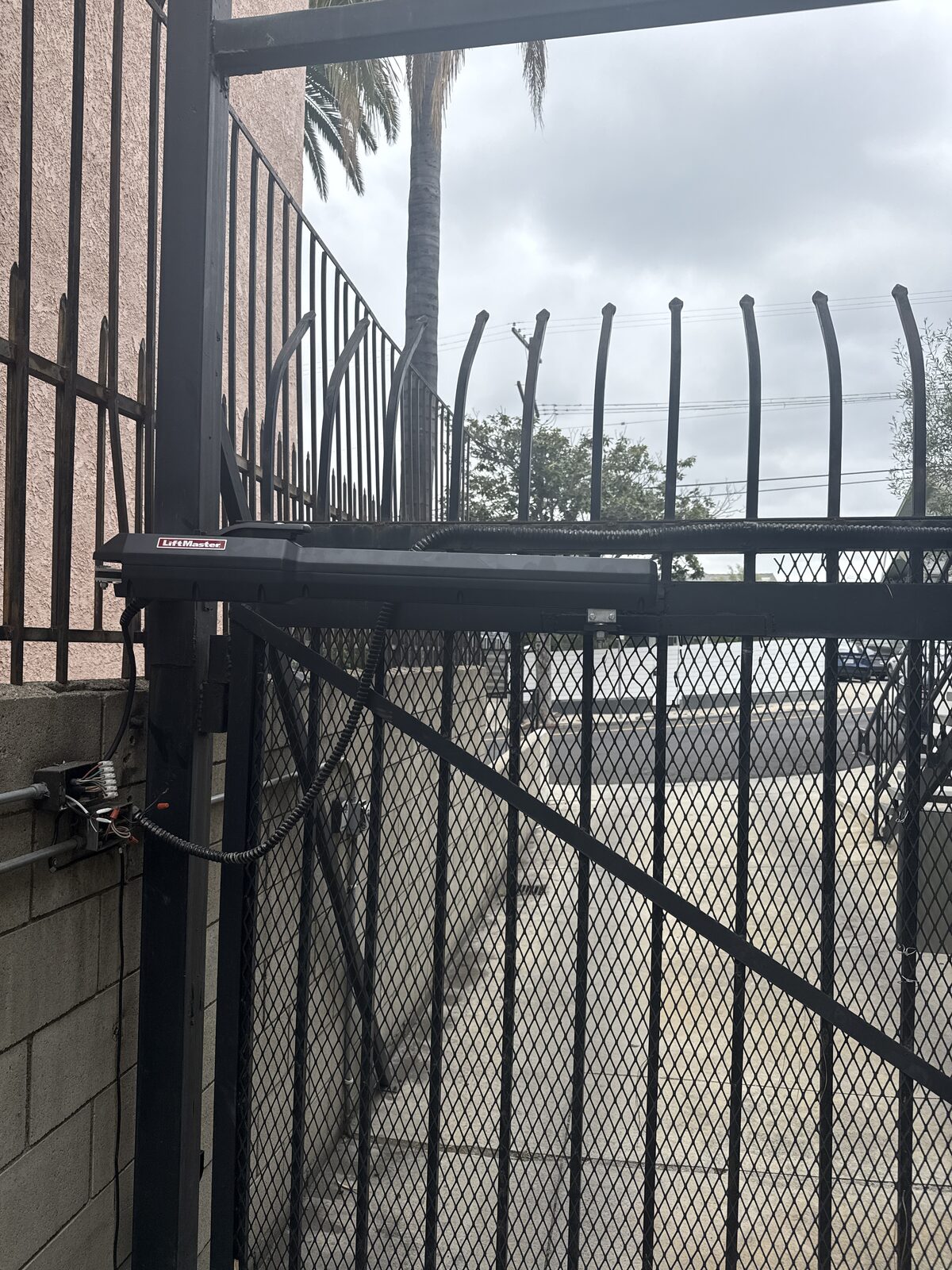 Black steel swing driveway gate with linear actuator arm installed by Metro GDS in Los Angeles