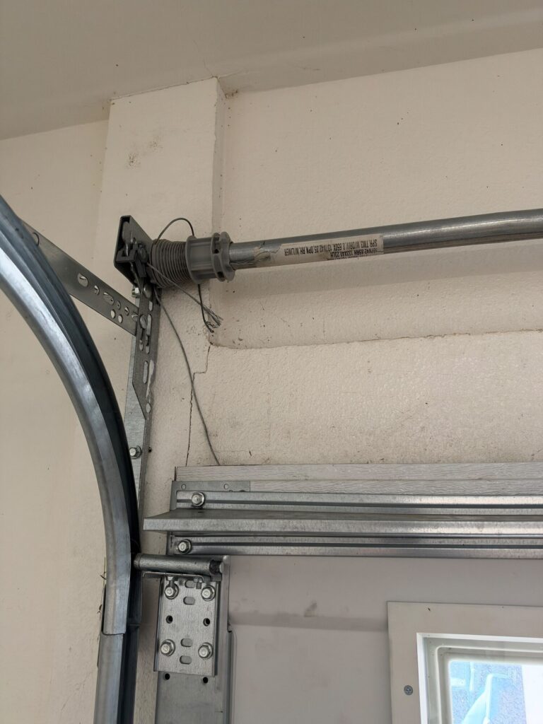 Torsion tube end with cable drum and track curve on a sectional garage door serviced by Metro GDS in Los Angeles