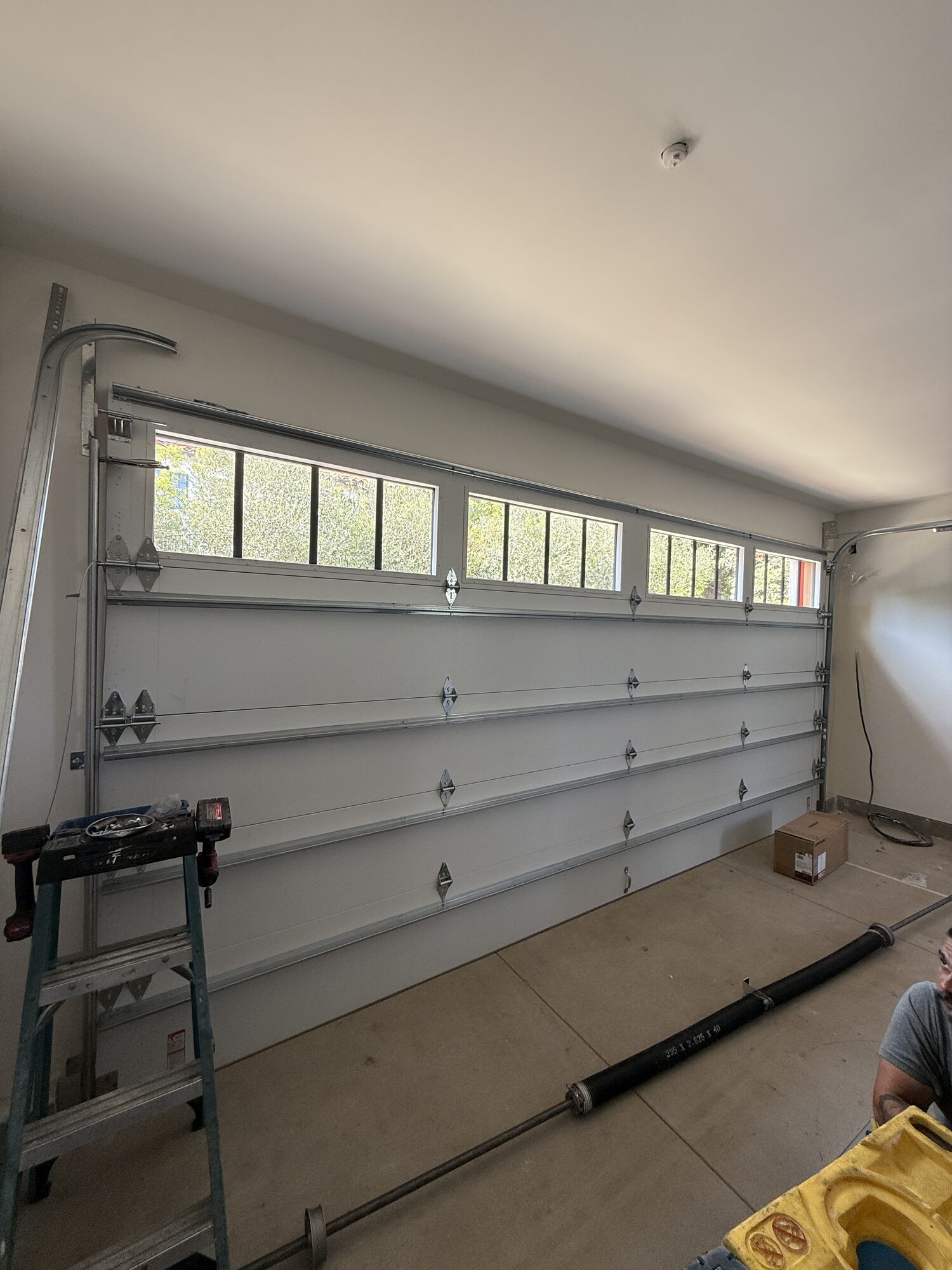Inside a garage showing a sectional door with torsion tube and track serviced by Metro GDS in Los Angeles
